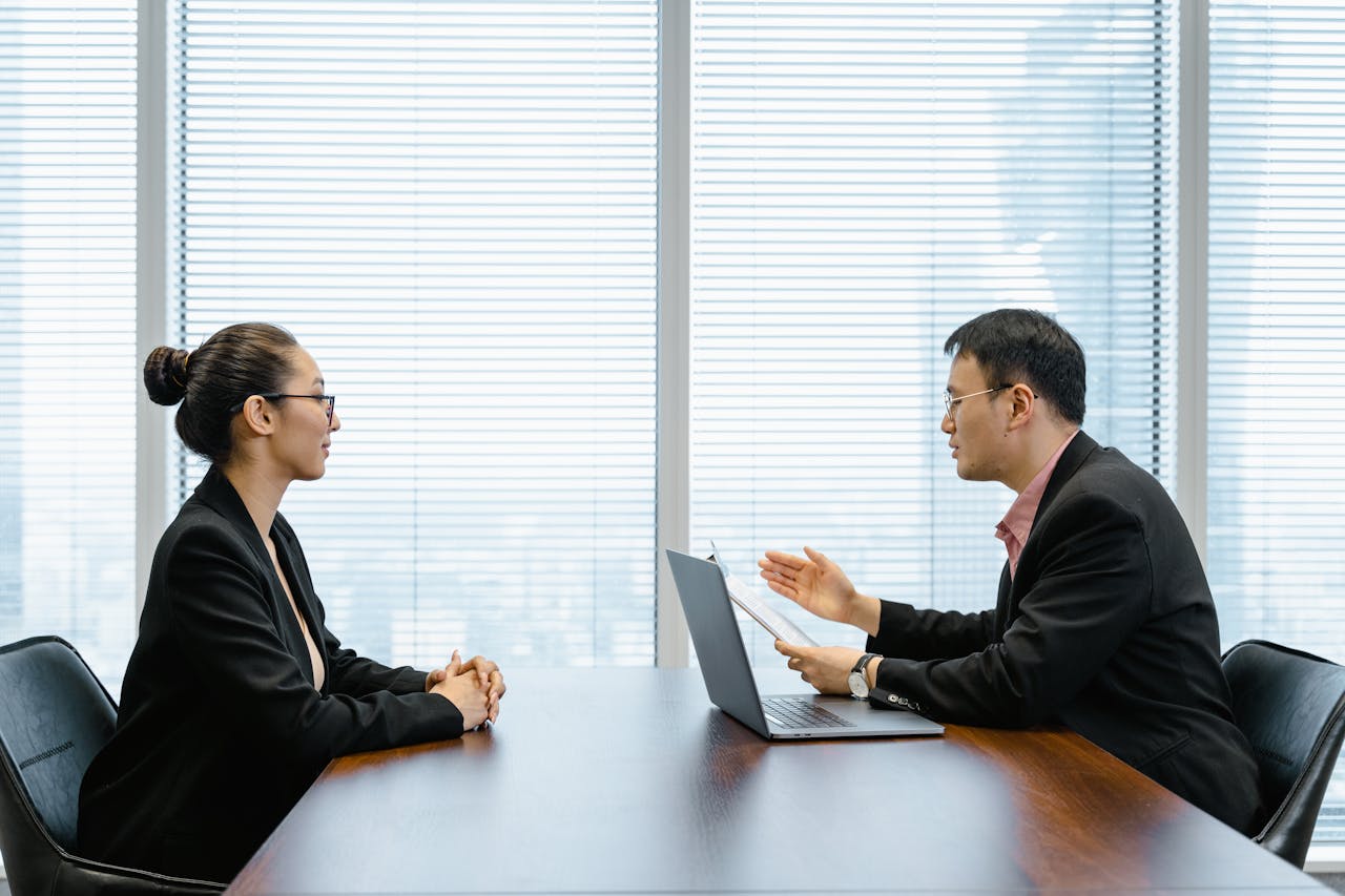 Two businesspeople engaged in a discussion during a professional meeting in an office setting.
